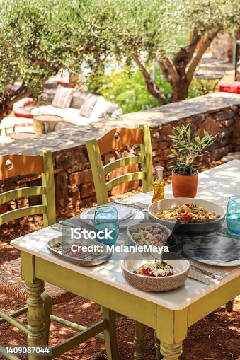 istock Greek Dinner Table with Food and Plates under olive trees with Cretan delicacies 1409087044