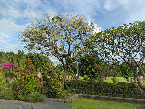 The gardens at Puputan Badung Square are beautiful and crowded with people visiting.