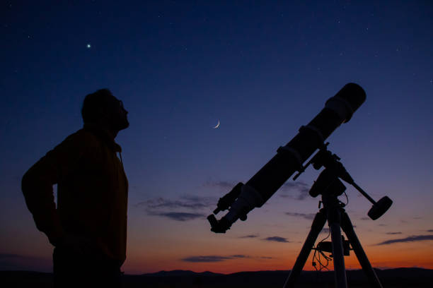 istock Man with astronomical telescope observing night sky, under the Milky way stars. 1409090584