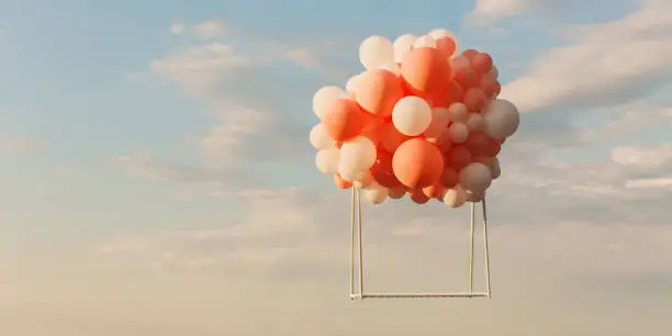 Photo of Swing flying through air against background of blue sky with clouds. White and pink balloons. Conceptual photography