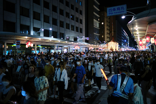 Kyoto, Japan - July 16, 2022: People crowd Shijo Street to view the ceremonial yamaboko floats on the night before the Sunday parade at the Gion Festival. Hundreds of thousands came to the area in the evenings leading up to the procession.