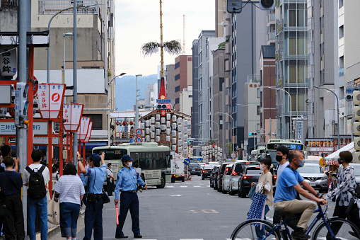 Kyoto, Japan - July 16, 2022: Police direct foot traffic along Shijo Street during the Gion Festival. The street was closed off to automobile traffic later in the day.