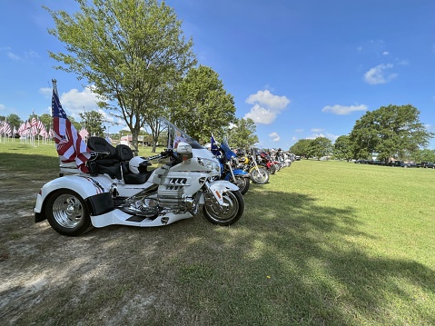 ocean pines, maryland, usa - may 30,2022 : A line of motorcycles displaying the American flag line the Ocean Pines, MD park with an array of American flags in the background for Memorial Day festivities
