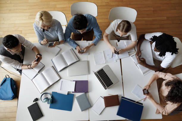 istock Overhead view multiethnic students sit at table use smartphones 1409098793