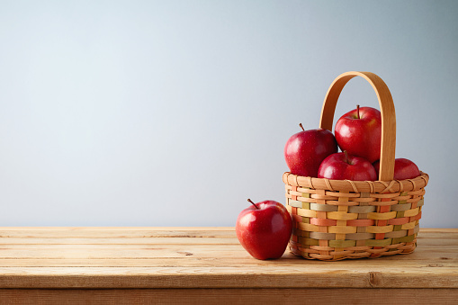 Kitchen table with red apples in basket. Interior decoration background mock up for design and product display