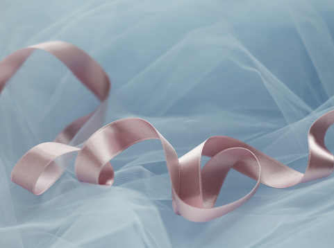 Beautiful pastel-colored ribbon twisted on light blue tulle fabric. Top view