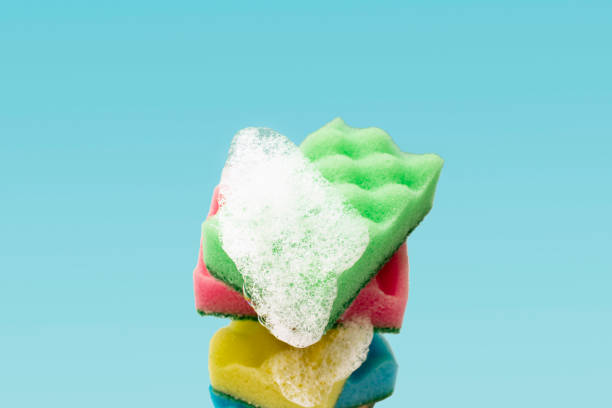 istock Stack of colorful kitchen cleaning sponges with soap bubbles on blue background. 1409114791