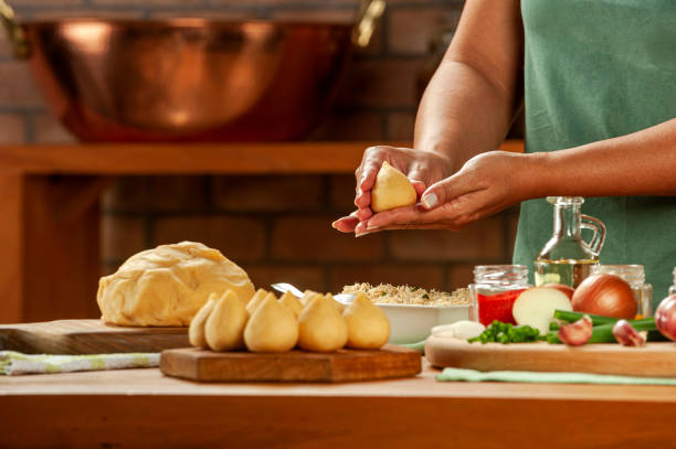 Brazilian chicken croquette - Chicken coxinha Woman hands preparing brazilian chicken croquette (coxinha de frango) on a wooden table. coxinha stock pictures, royalty-free photos & images