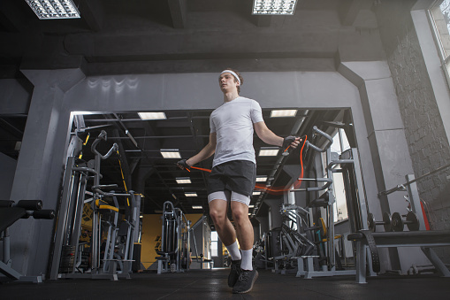 Low angle shot of a sportsman skipping on jumping rope at gym