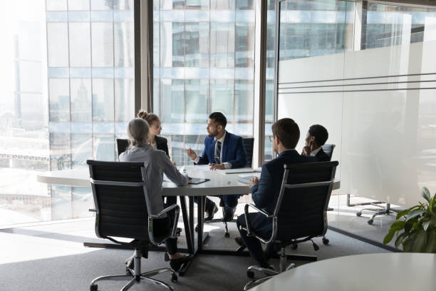 Five multi ethnic business people negotiating in modern boardroom stock photo