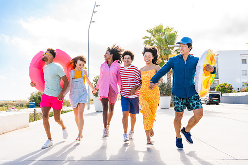 Multiethnic group of young happy friends bonding outside, having fun on summertime vacation - Multicultural cheerful people with summer clothes enjoying summer holidays, concepts about youth, friendship and positive emotion
