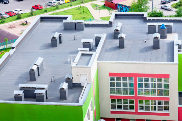 Top view dark flat roof with air conditioners and hydro insulation membranes modern school building residential area. stock photo