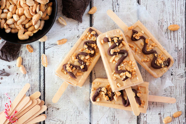 Peanut butter popsicles above view table scene over white wood