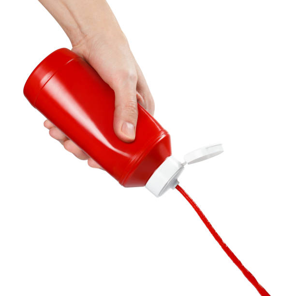 istock Hand squeezing ketchup out of a plastic bottle on white 1409140743