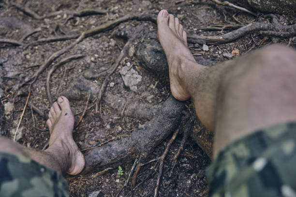 istock Man sitting barefoot in the forest 1409144406