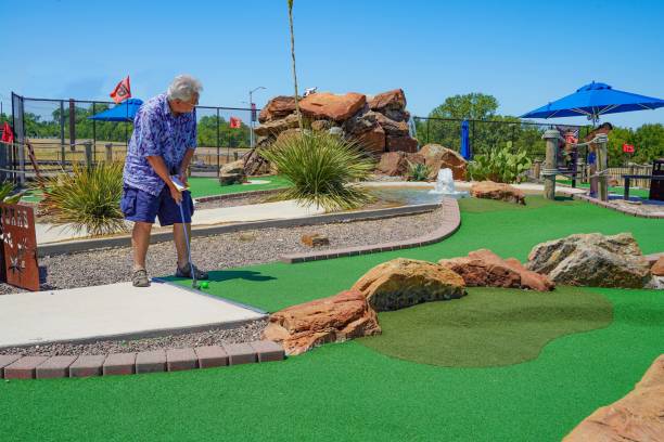 Senior Man Plays Miniature Golf Senior Man Plays Miniature Golf. Copy Space. christine kohler stock pictures, royalty-free photos & images