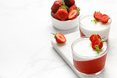 Strawberry creamy dessert - panna cotta with strawberry in a glass jars decorated with fresh berries and mint, Traditional Italian sweet dessert.