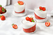 Strawberry creamy dessert - panna cotta with strawberry in a glass jars decorated with fresh berries and mint. Traditional Italian sweet dessert.