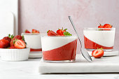 Strawberry creamy dessert - panna cotta with strawberry in a glass jars decorated with fresh berries and mint. Traditional Italian sweet dessert.
