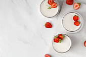 Strawberry panna cotta creamy dessert - panna cotta with strawberry in a glass jars decorated with fresh berries and mint. Traditional Italian sweet dessert.