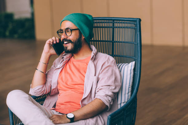 un sonriente y guapo hombre de negocios barbudo que llama a alguien usando su teléfono móvil mientras está sentado al aire libre - businessman 30s low key surprise fotografías e imágenes de stock