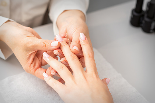 Tratamiento de manicura en el spa de belleza. Una mano de una mujer recibiendo un masaje de dedos con aceite en un salón de uñas. photo