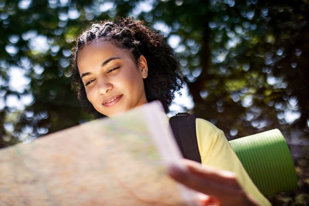istock Young woman hiking in nature looking at map 1409153580