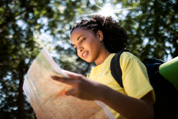 istock Young woman hiking in nature with backpack looking at map 1409153603
