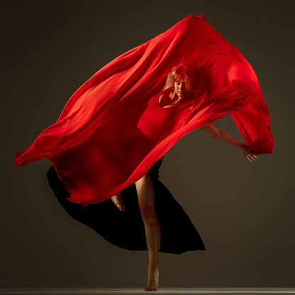 dancer with red textile in motion, face visible through textile