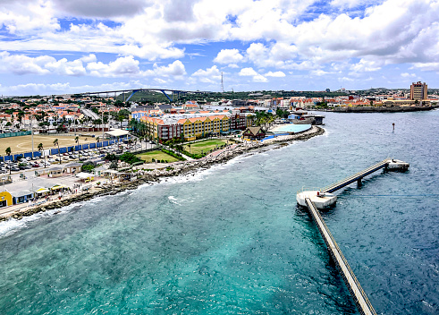 Arriving by cruise ship at the Willemstad, the capital of Curaçao (which is part of the Kingdom of the Netherlands),  we see the Cruise Terminal Welcome Center, pier extensions, hotels and condominiums, a ball field, and it's famous Queen Juliana bridge over the St Anna Bay