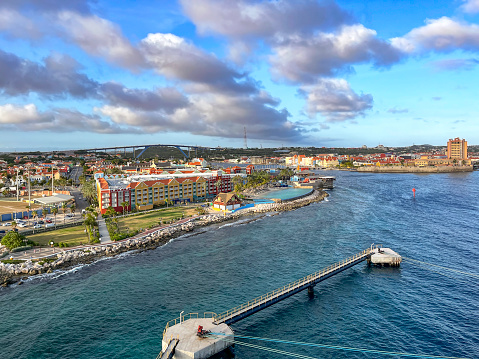 Arriving by cruise ship at the Willemstad, the capital of Curaçao (which is part of the Kingdom of the Netherlands),  we see the Cruise Terminal Welcome Center, pier extensions, hotels and condominiums, a ball field, and it's famous Queen Juliana bridge over the St Anna Bay