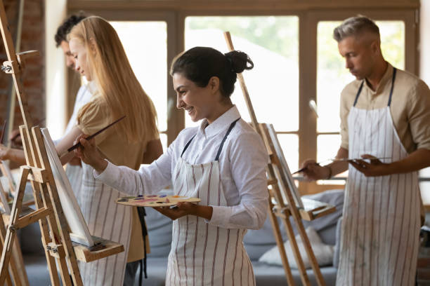 istock Indian woman painting on canvas during group art class 1409155367