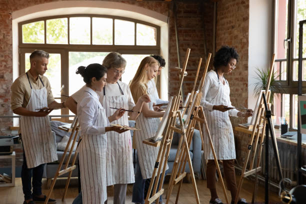istock Group of diverse people painting on easel during art-class 1409155368