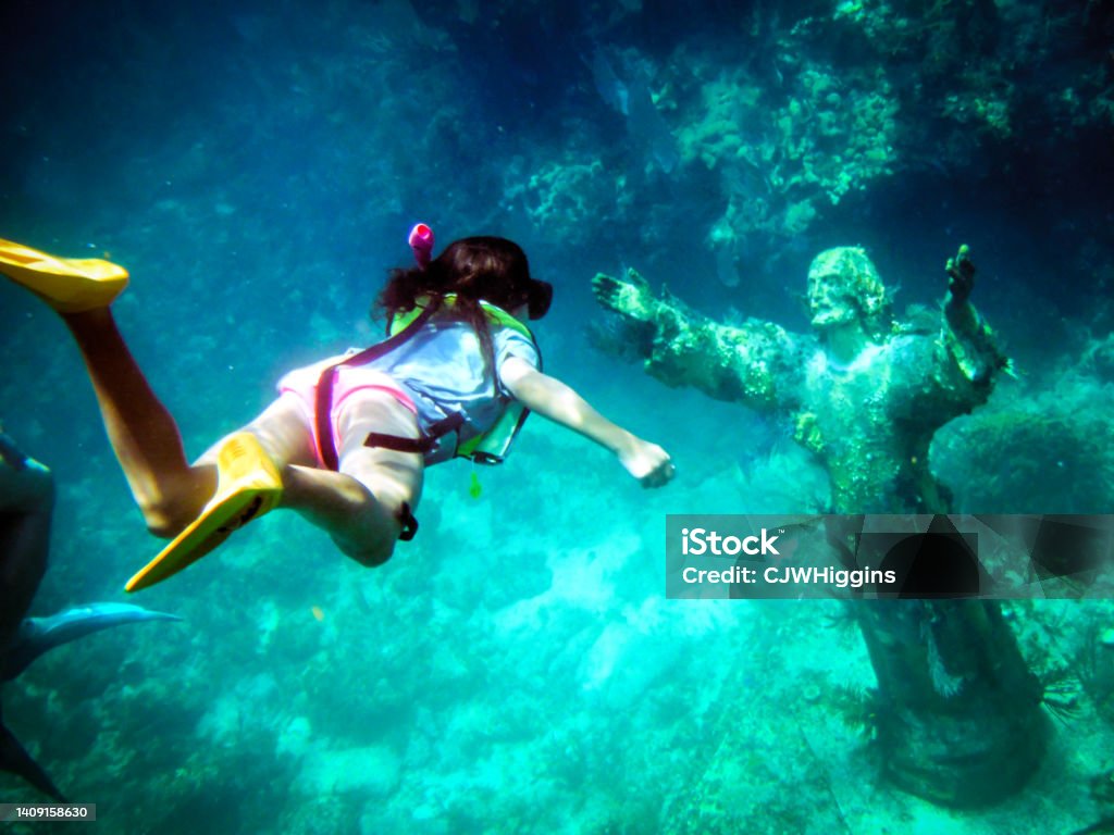 Girl Snorkeling to Christ of the Abyss Statue off Key Largo Florida Gulf of Mexico Underwater shot of a young girl snorkeling to the Christ of the Abyss Statue off Key Largo Florida Gulf of Mexico with fish swimming around and plant life growing. Key Largo Stock Photo