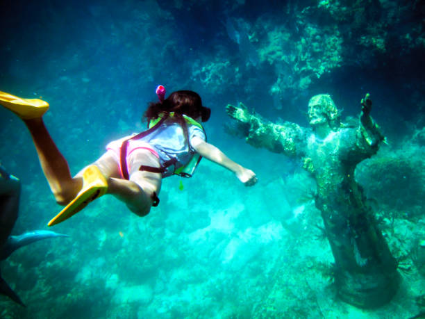 Girl Snorkeling to Christ of the Abyss Statue off Key Largo Florida Gulf of Mexico Underwater shot of a young girl snorkeling to the Christ of the Abyss Statue off Key Largo Florida Gulf of Mexico with fish swimming around and plant life growing. key largo stock pictures, royalty-free photos & images