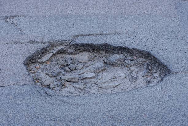 istock one big pothole on the gray asphalt road 1409168208