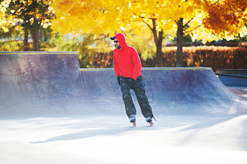 Middle age man roller skating outdoors in autumn park