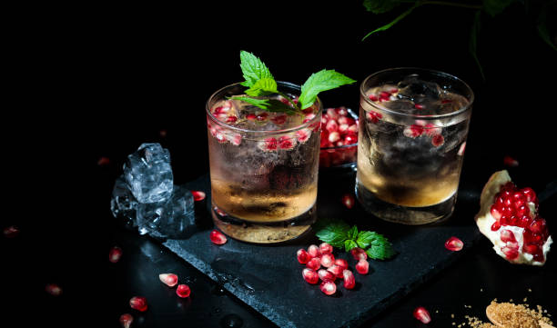 two colorful summer drinks with mint, pomegranate and ice cubes on a black background stock photo
