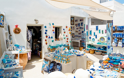 Santorini , Greece - June 05, 2022: Beautiful souvenir shops on typical colorful narrow street in Oia, the most beautiful village of Santorini island, Greece