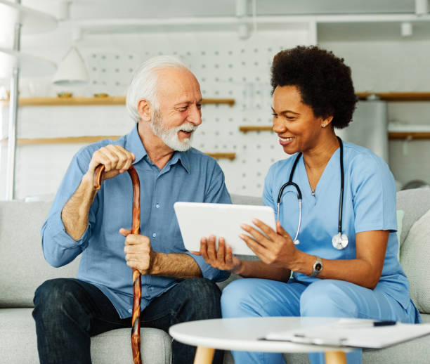 istock nurse doctor senior care tablet computer technology showing caregiver help assistence retirement home nursing elderly woman african american black happy laughing man 1409179339