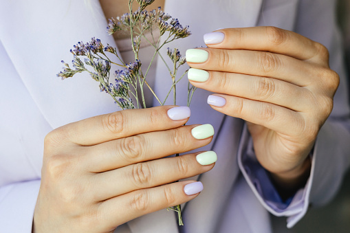 Beautiful purple manicure on a milky background with flowers.