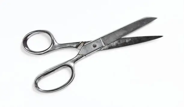Photo of Old and rusty metallic scissors isolated on white background. Silver clippers