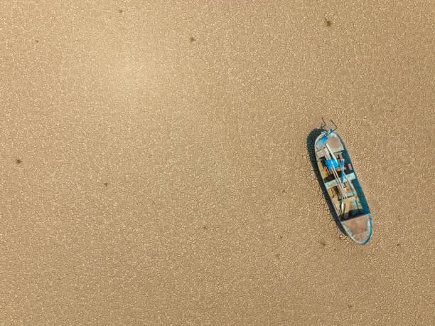 Aerial view of a fishing boat on a drought dry lakebed. Aerial view of a single fishing boat on the dry surface of a drought lake bed. Taken via drone. Burdur,  Turkey. lakebed stock pictures, royalty-free photos & images