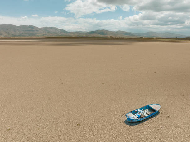 Aerial view of a fishing boat on a drought dry lakebed. Aerial view of a single fishing boat on the dry surface of a drought lake bed. Taken via drone. Burdur,  Turkey. lake bed stock pictures, royalty-free photos & images