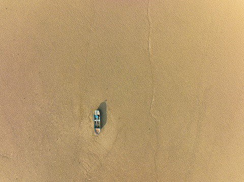 Aerial view of a single fishing boat on the dry surface of a drought lake bed. Taken via drone. Burdur,  Turkey.