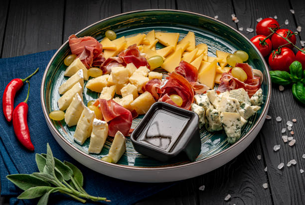 cheese platter with different cheese, jamon, prosciutto and grapes. - italian cuisine wine food pasta imagens e fotografias de stock