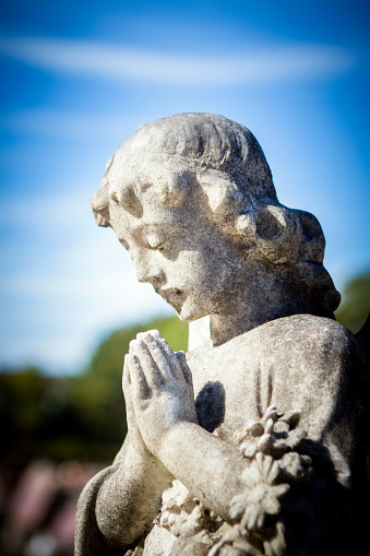 Old statue of Praying angel from cemetery, background with copy space, full frame vertical composition