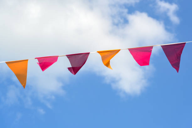 istock Pennants in warm colors hanging on a line between against a blue sky with clouds, decoration for a summer party or festival, copy space 1409186241