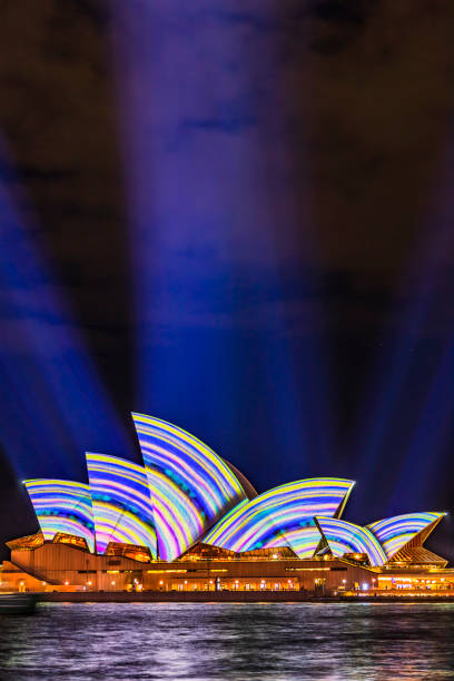 Sydney, Australia - August 25, 2025: Early morning in Sydney, and the iconic Opera House and a cloudy pre-dawn sky are reflected in the waters of Circular Quay. The long exposure captures a distant ferry passing the Opera House.