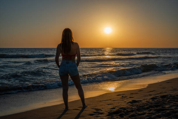 istock woman on her back watching a sunset on the beach 1409194033